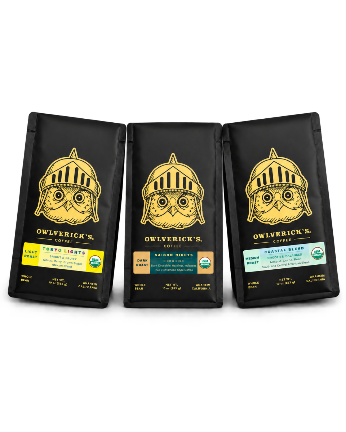 Three black bags of Owlverick's Coffee arranged side by side on a white background, each featuring a gold owl-in-helmet logo and a different label: Tokyo Lights, Saigon Nights and Coastal Blend.